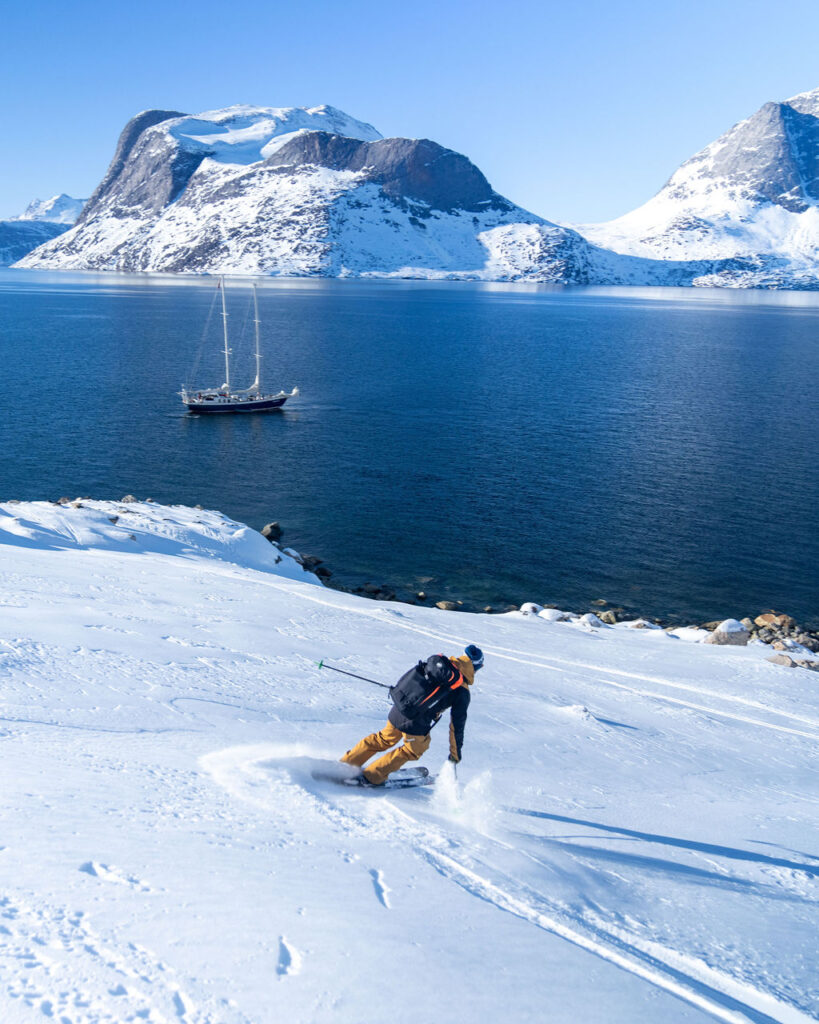 Skier making their way through rugged, snow-covered mountains in Greenland.