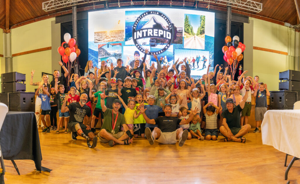 A group of diverse individuals smiling and posing together in front of a large screen displaying colorful graphics.