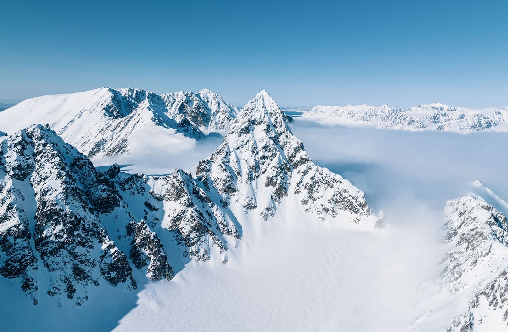 Snow-covered mountains with an explorer trekking through the Arctic landscape.