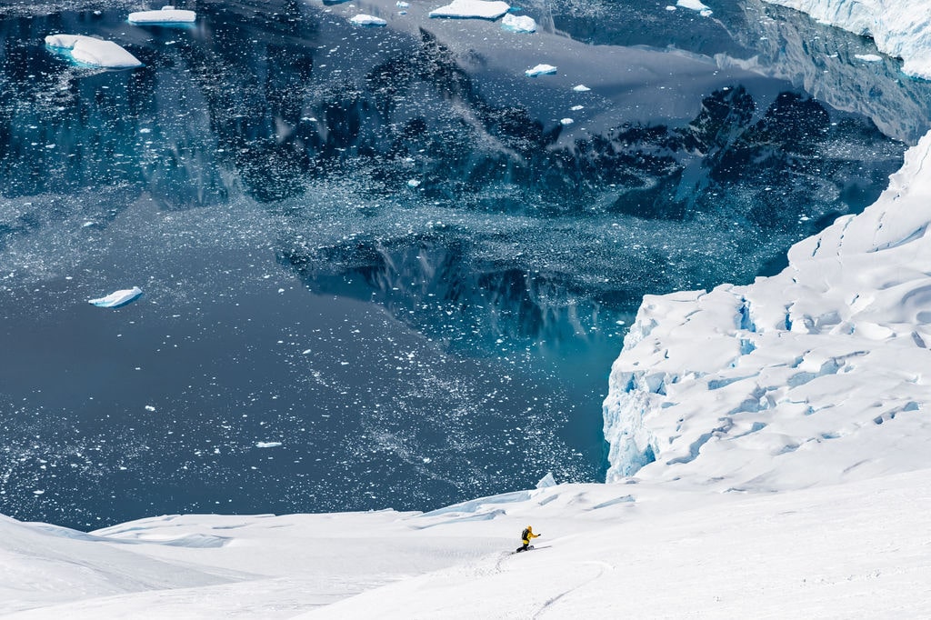 Snow-covered terrain in Antarctica with an explorer in the distance